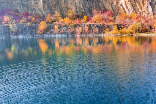 Panoramic top view quarry artificial lake formed during mining stone in autumn season