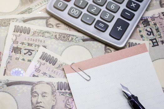 fountain pen, empty paper and calculator with ten thousand yen banknote, for business and financial concept.