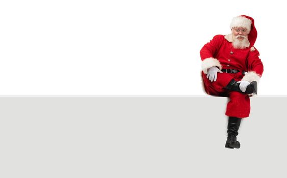 Santa Claus sitting on a blank panel isolated on white background