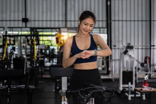 Beautiful sporty woman using smart watch checking notify between sports training at gym.