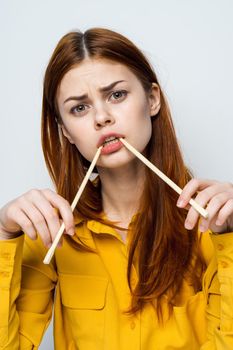 woman eating sushi with japanese chopsticks posing light background. High quality photo