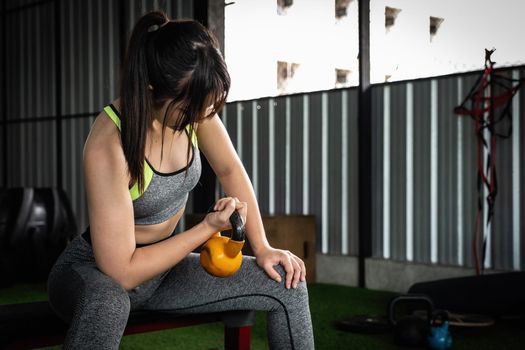 Young asian female enjoy exercising with lifting kettle bell with one hand at the gym. sport bodybuilding concept