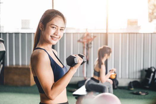 Fitness girl lifting dumbbell in the gym, asian woman workout in morning