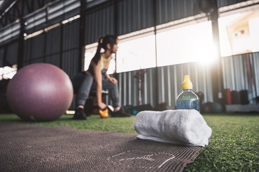 Selective focus towel and water bottle with woman workout fitness background