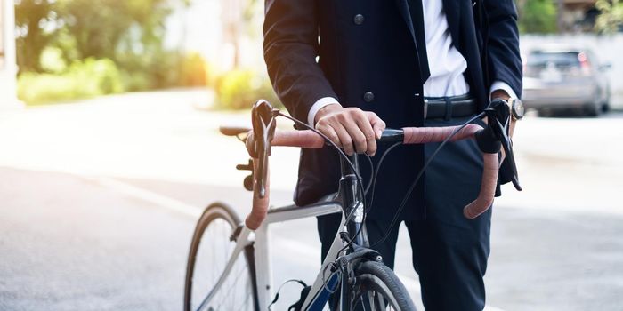 Handsome young asian businessman in suit have smiling with bicycle go to work at morning.