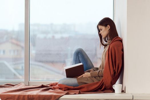 woman with a book near the window with a cup of coffee. High quality photo