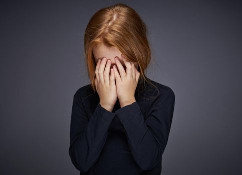red-haired girl with freckles on her face in a black sweater posing. High quality photo
