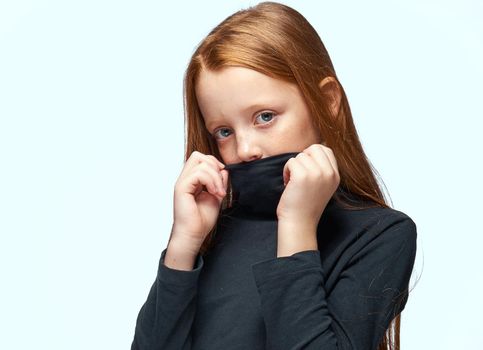 girl in a black sweater red hair posing light background. High quality photo