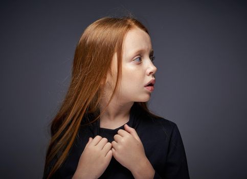 red-haired girl with freckles on her face in a black sweater posing. High quality photo