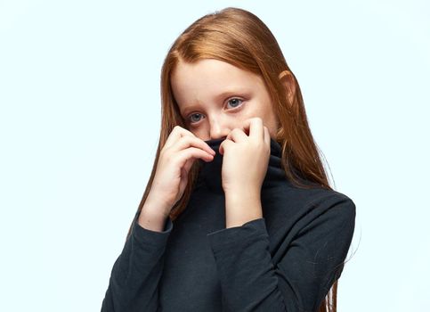girl in a black sweater red hair posing light background. High quality photo