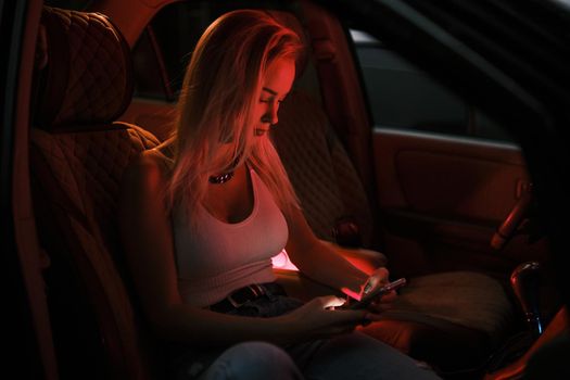 A beautiful girl of European appearance sits on the passenger seat in the car and looking to the window