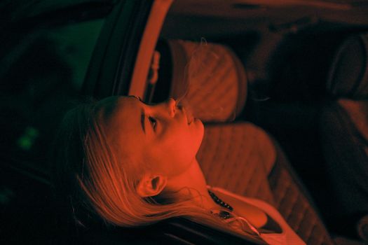 A beautiful girl of European appearance sits on the passenger seat in the car and looking to the window