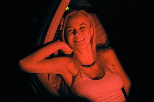 A beautiful girl of European appearance sits on the passenger seat in the car and looking to the window