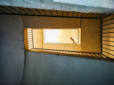 Upward view to spiral square staircase in old tenement house on Capri island