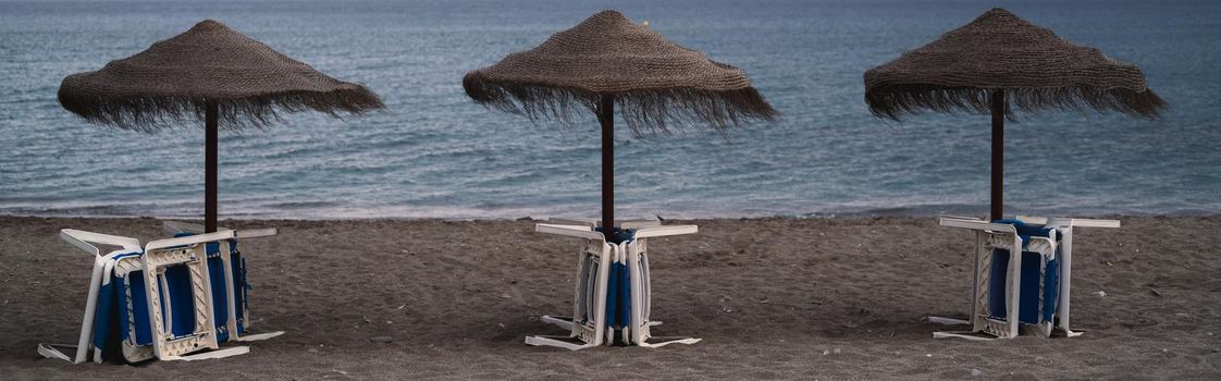 beach umbrellas with hammocks gathered in front of the sea on a overcast day. end of summer concept.