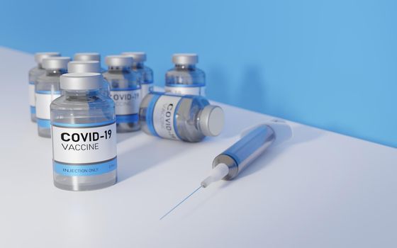 CORONAVIRUS VACCINES WITH A SYRINGE ON A WHITE TABLE WITH A BLUE WALL