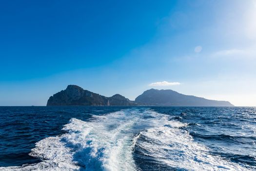 Silhouette of Capri island on Thrrhenian Sea in Italy seen from boat with waves behind