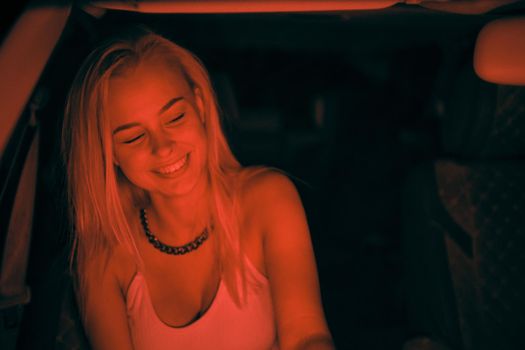 A beautiful girl of European appearance sits on the passenger seat in the car and looking to the window