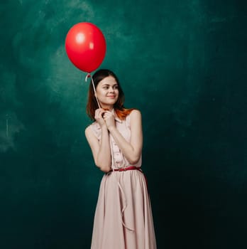 woman with red balloon on green background holiday fun. High quality photo