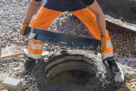 Sewerage construction with utility worker installing underground well of manhole sewage
