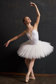 woman ballerina in a white tutu dance posing performance dark background. High quality photo