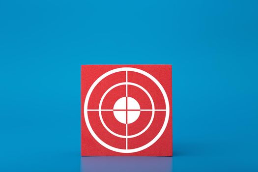 Goal symbol on red toy cube in the middle of dark blue background. Concept of goal, success, reaching business and personal aims