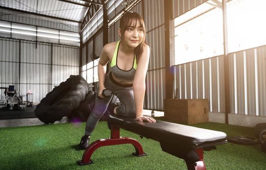 A stunning Asian woman concentrates on lifting a dumbbell at the gym. weight training.