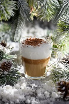 Christmas latte macchiato. A great hot coffee drink with chocolate shavings, among the snow-covered pine branches and snow.