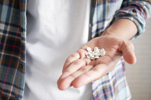 man's hand with pills spilled out of the container .