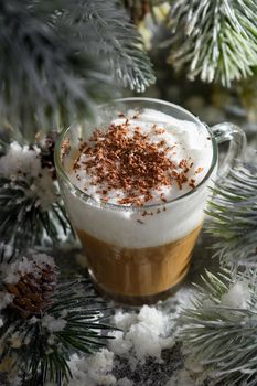 Christmas latte macchiato. A great hot coffee drink with chocolate shavings, among the snow-covered pine branches and snow.