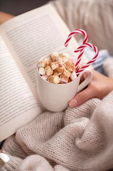 Christmas magic scene, cozy atmosphere. 
Woman holding cup of drink with marshmallows. 
