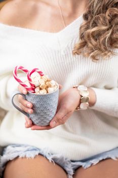 Christmas magic scene, cozy atmosphere. 
Woman holding cup of drink with marshmallows. 