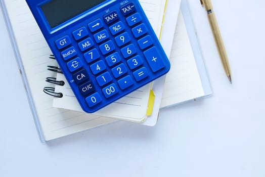 Top view of note pad, calculator, pen on white background