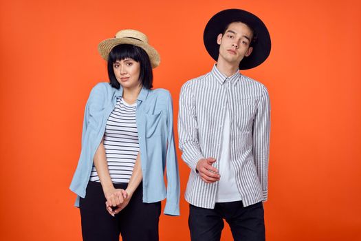 man and woman in hats posing fashion orange background. High quality photo