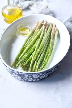 Asparagus green in a bowl with oil on table .