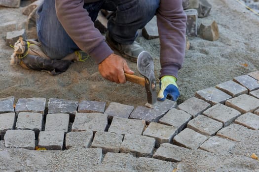 Paving pavement with granite stones, workers using industrial cobblestones for paving road with worker using hammer