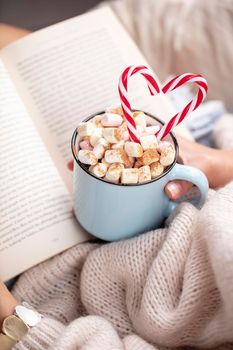 Christmas magic scene, cozy atmosphere. 
Woman holding cup of drink with marshmallows. 