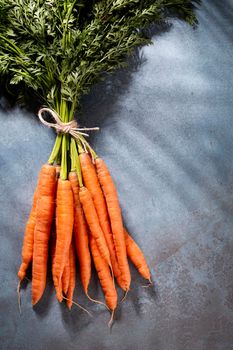 Organic carrot on wood cutting board, closeup photo.