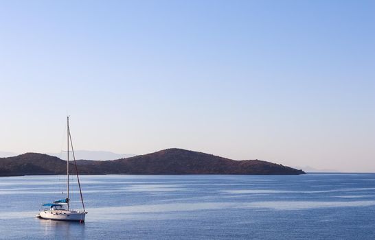 Blue sea, a boat and mountains in sunrise. Tranquil seascape and coastal nature concept