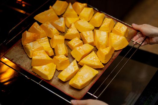 Pumpkin slices baked on a baking sheet in the oven. Homemade food, Vegan food, Healthy food, orange vegetables on a baking sheet and napkin, baked rustic vegetables, pop art, dessert during a diet