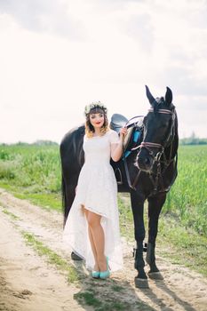 girl with red lips in a white dress near a black horse