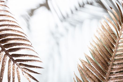 Gold palm leaves and shadows on a blue wall background.