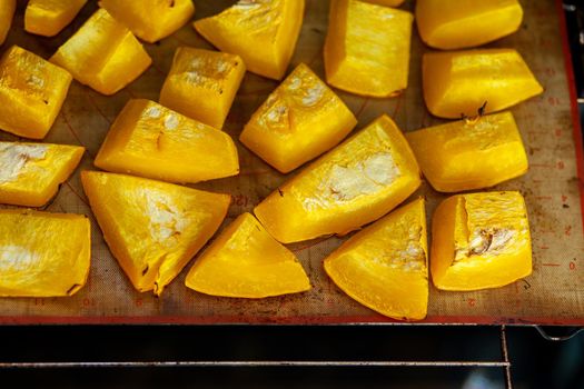 Pumpkin slices baked on a baking sheet in the oven. Homemade food, Vegan food, Healthy food, orange vegetables on a baking sheet and napkin, baked rustic vegetables, pop art, dessert during a diet