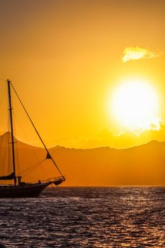 Beautiful sunset on the Aegean Sea with mountains and a sailboat. Seascape, travel and nature concept. High quality photo