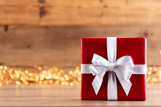 Christmas gift boxes with ribbons and tree on bokeh background.