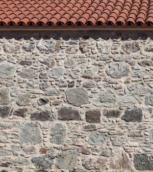 Part of an old stone wall and roof. Natural background or texture. High quality photo.