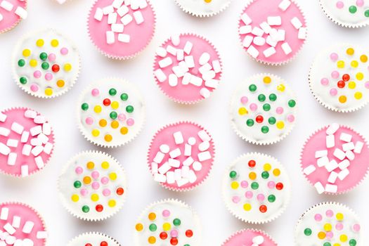 Multiple colorful nicely decorated muffins on a white background, top view.