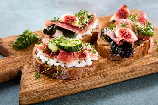 Variety of mini sandwiches with cream cheese, vegetables and salami. 