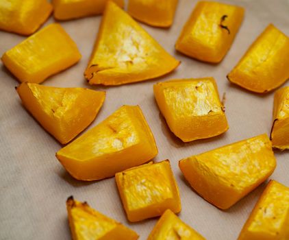 Pumpkin slices baked on a baking sheet in the oven. Homemade food, Vegan food, Healthy food, orange vegetables on a baking sheet and napkin, baked rustic vegetables, pop art, dessert during a diet