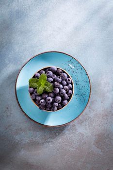 Bowl of fresh blueberries on rustic wooden board. Organic food blueberries and mint leaf for healthy lifestyle.